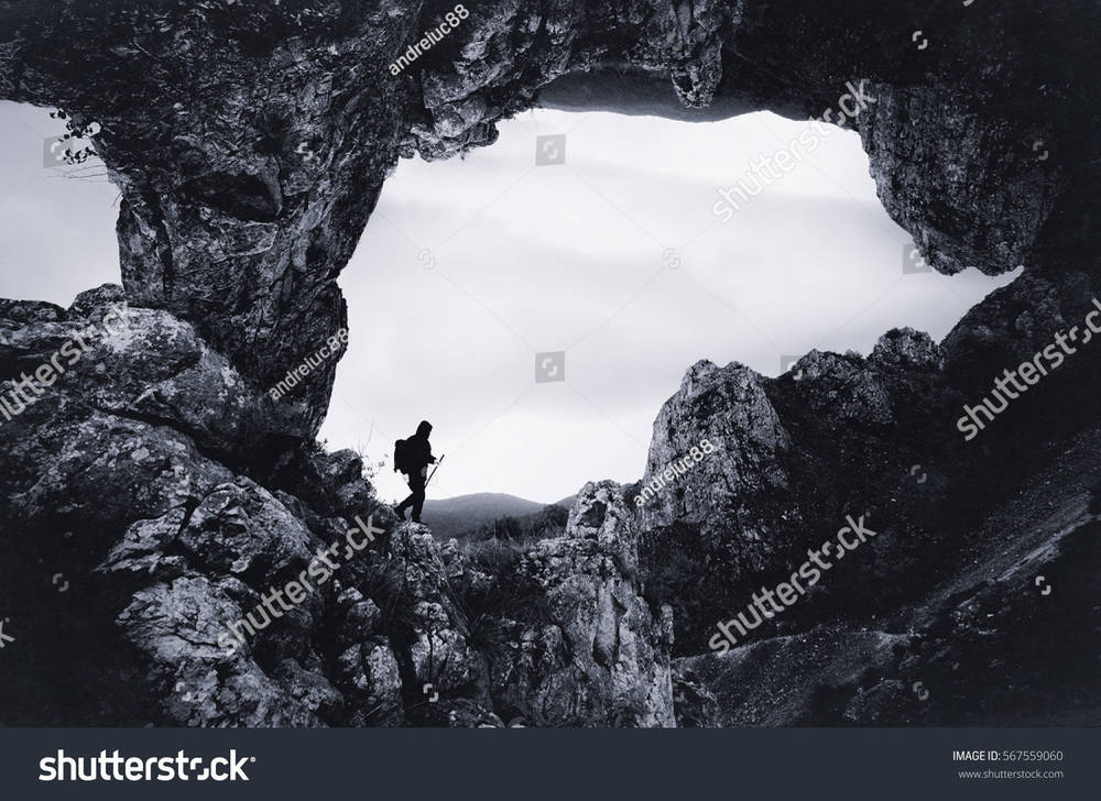 stock-photo-surreal-landscape-with-man-exploring-big-cave-567559060.jpg